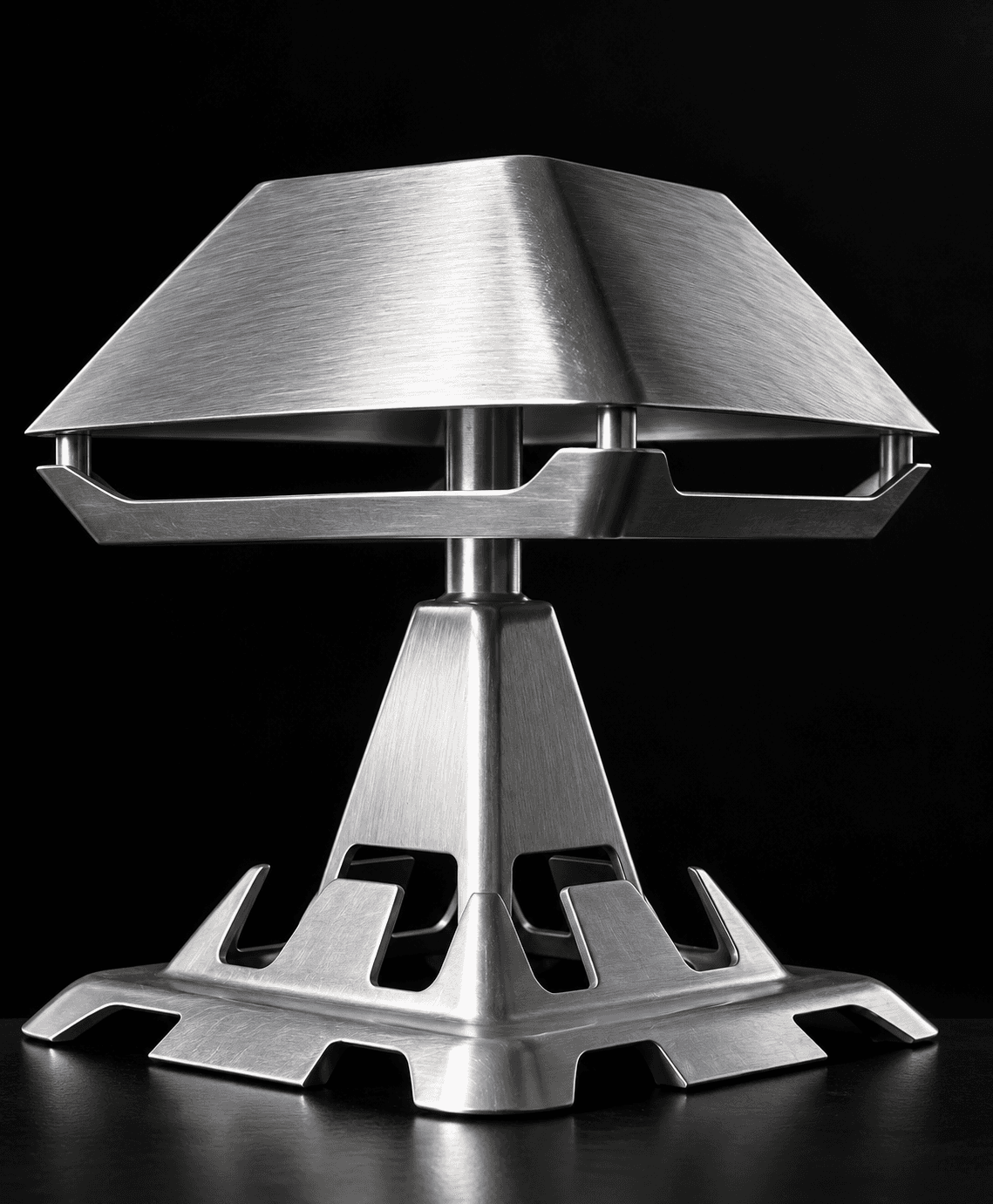 Turn Me On: a brushed cast-aluminium table lamp with a wide, low shade, on a pyramid stem and a notched square base.