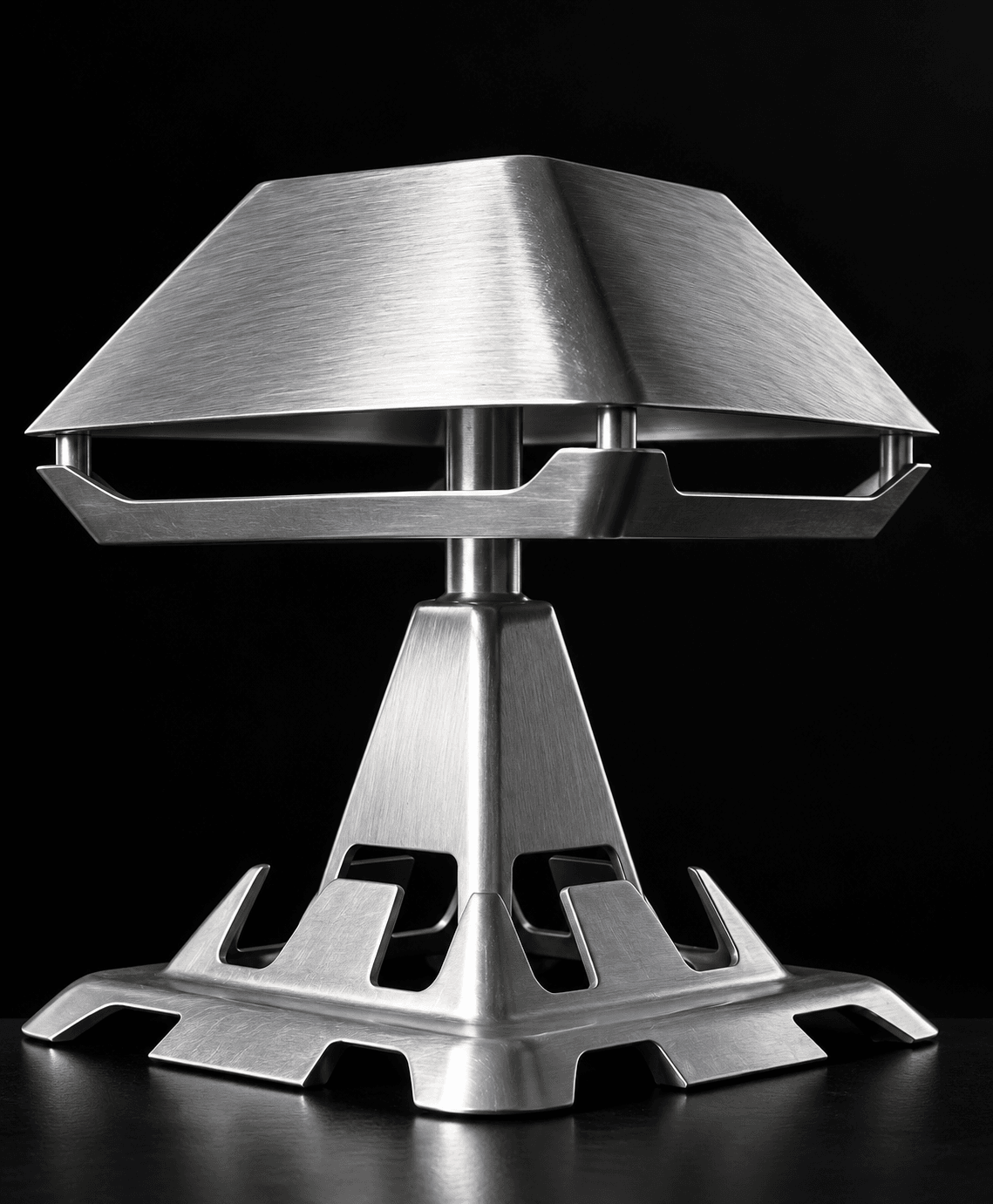 Turn Me On: a brushed cast-aluminium table lamp with a wide, low shade, on a pyramid stem and a notched square base.